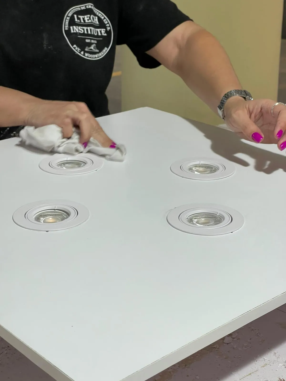 Estudiante limpiando un plafón de gypsum con luces LED empotradas.