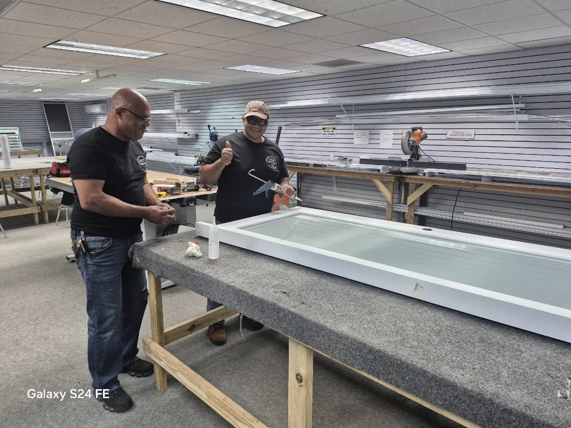 Estudiantes trabajando una ventana de aluminio con cristal en la mesa de trabajo.